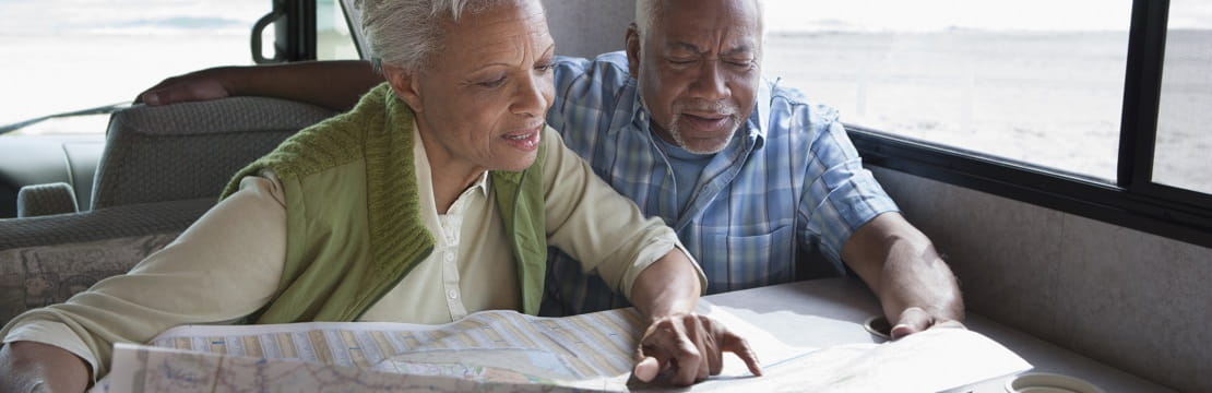 Couple looks at a paper map while sitting at the table in a mobile home